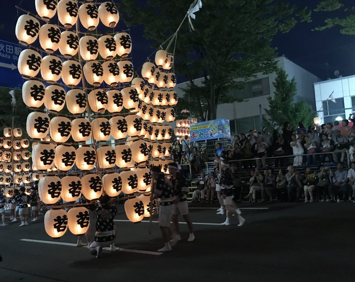 Akita Kantō Festival poles hung with dozens of glowing paper lanterns at night, near Akita Station